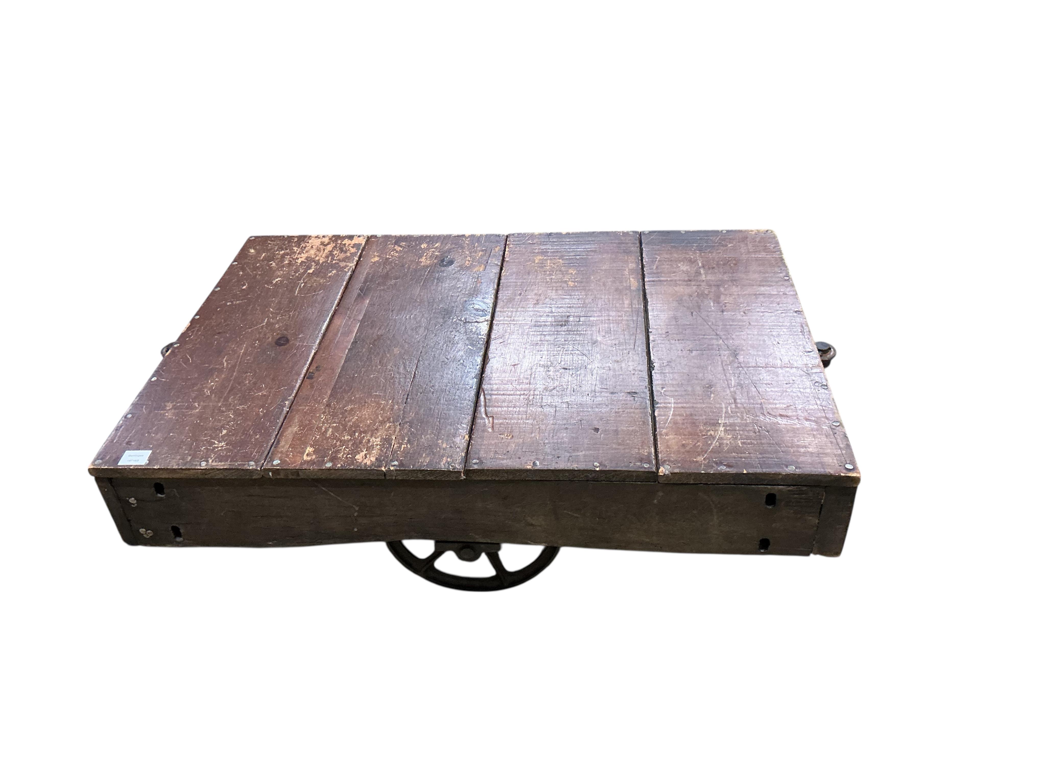 A vintage rectangular wood factory cart with iron spoked wheels now as a coffee table, width 112cm, depth 76cm, height 35cm